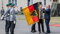 Boris Pistorius befestigt das Fahnenband an der Flagge. 