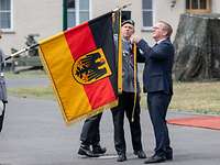 Boris Pistorius befestigt das Fahnenband an der Flagge. 