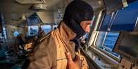 Ein Soldat mit einer Flammenschutzhaube auf der Brücke von einem Schiff der Deutschen Marine
