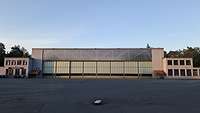 Eine lange flache Halle mit Anbauten rechts und links