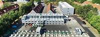 Kaserne mit Gebäuden im Hintergrund. Im Vordergrund werden drei Containergebäude aufgebaut.