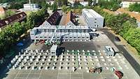 Kaserne mit Gebäuden im Hintergrund. Im Vordergrund werden drei Containergebäude aufgebaut.