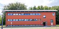 Zweigeschossiges, rotes Funktionsgebäude mit kleinen Fensterreihen und Satteldach