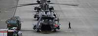 Vier Militärhubschrauber stehen teils mit eigeklappten Rotoren hintereinander