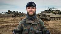 Soldat im Porträt im Hintergrund Panzer auf aufgewühltem Feld