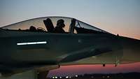Ein Pilot sitzt im Sonnenuntergang im Cockpit.