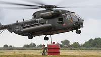 Ein Hubschrauber CH-53 nimmt einen Löschwasserbehälter auf.