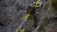 Ein Soldat klettert an einer Felswand.