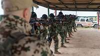 Ghanaische Soldaten mit Gewehren im Anschlag stehen in einer Reihe.