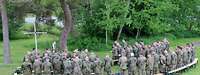 Soldaten stehen zum Feldgottesdienst der auf einer Wiese. Sie beten vor einem Birkenkreuz.