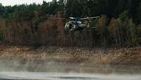 Ein Hubschrauber nimmt in einem Bucket Wasser zum Löschen an einem See auf