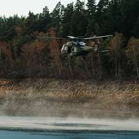 Ein Hubschrauber nimmt in einem Bucket Wasser zum Löschen an einem See auf