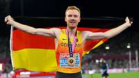 Stabsunteroffizier Frederik Ruppert läuft mit einer Deutschland-Flagge auf dem Rücken eine Ehrenrunde.