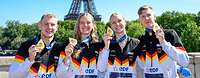 Vier junge Sportler posieren mit ihren Goldmedaillen, im Hintergrund der Eifelturm in Paris.