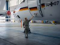 Ein Fluggerätemechaniker öffnet die Tür eines Flugzeugs.