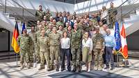 Zivilisten und Soldaten unterschiedlicher Nationen stehen für ein Gruppenfoto zusammen.