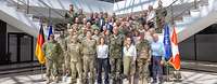 Zivilisten und Soldaten unterschiedlicher Nationen stehen für ein Gruppenfoto zusammen.