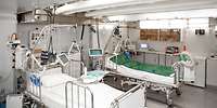 Zwei Krankenhausbetten und mehrere medizinische Geräte stehen in einem Containerraum.