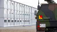 Ein Unterkunftsgebäude in Modulbauweise, im Vordergrund ein Bundeswehr-Fahrzeug