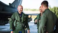 Zwei Piloten der Bundeswehr und der Astronaut Alexander Gerst stehen zusammen und unterhalten sich.