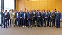 Eine Gruppe Männer in einem Saal nebeneinanderstehend