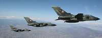  Drei deutsche Tornado-Kampfflugzeuge fliegen in enger Formation über einer trockenen, gebirgigen Landschaft.
