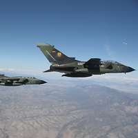  Drei deutsche Tornado-Kampfflugzeuge fliegen in enger Formation über einer trockenen, gebirgigen Landschaft.