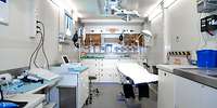 Blick in einen Containerraum mit Schränken, Patientenliege und Geräten