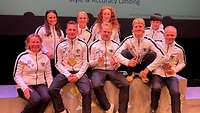 Sportlerinnen und Sportler sitzen auf einer Bühne