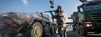 Ein Militärisches Fahrzeug wird durch einen Soldaten in ABC Schutzkleidung gereinigt.