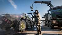 Ein Militärisches Fahrzeug wird durch einen Soldaten in ABC Schutzkleidung gereinigt.