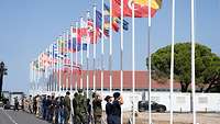 Mehrere Soldaten stehen vor allen Flaggen der NATO Partnerstaaten