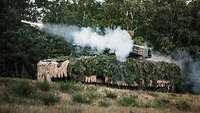 Ein Panzer vom Typ Puma steht im Gelände und feuert eine Rakete ab.
