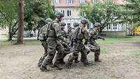 Mehrere Soldaten tragen einen verwundeten Soldaten in einem Tuch bei einer Übung.