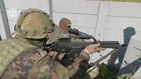 Zwei vermummte Soldaten mit Gewehren im Anschlag gehen durch einen Graben.