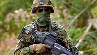 Ein vermummter Soldat mit Gewehr im Porträt