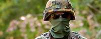 Portrait of a masked soldier with a rifle.