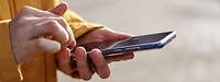 Eine Frau hält ein Handy in der Hand.