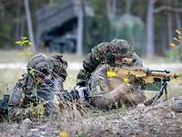 Zwei deutsche Soldaten liegen mit ihren Waffen im Anschlag, im Hintergrund ein schwedisches Waffensystem
