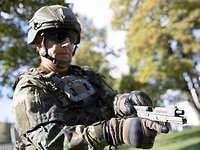 Ein Soldat hält eine Pistole P13 in der Hand und zieht am Verschluss.
