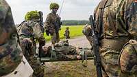 Soldaten tragen einen Übungsverletzten auf einer Trage.