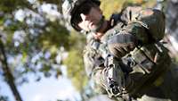 Ein Soldat hält eine Pistole P13 vor sich in den Händen.