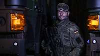 Ein Soldat steht zwischen zwei grünen Bundeswehr-LKWs