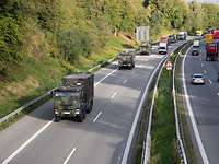 Militärische Fahrzeuge fahren in einer Kolonne auf einer Straße