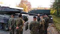 Eine Gruppe von Soldatinnen und Soldaten mit Englischlehrer an einem Kampfpanzer.