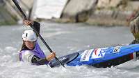 Eine Sportlerin sitzt in einem Kajak und paddelt durch das Wasser.
