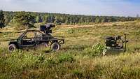 Ein offenes Radfahrzeug und eine kleine grüne Plattform stehen auf einer bewachsenen Fläche.