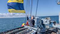 Ein Marine Soldat der eine Flagge auf einem Schiff hisst