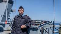 Ein Marine Soldat steht vor einem Flaggentisch auf einem Schiff