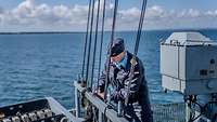 Ein Marine Soldat beim Vorbereiten aufm Schiff eine Signalflagge zu hissen